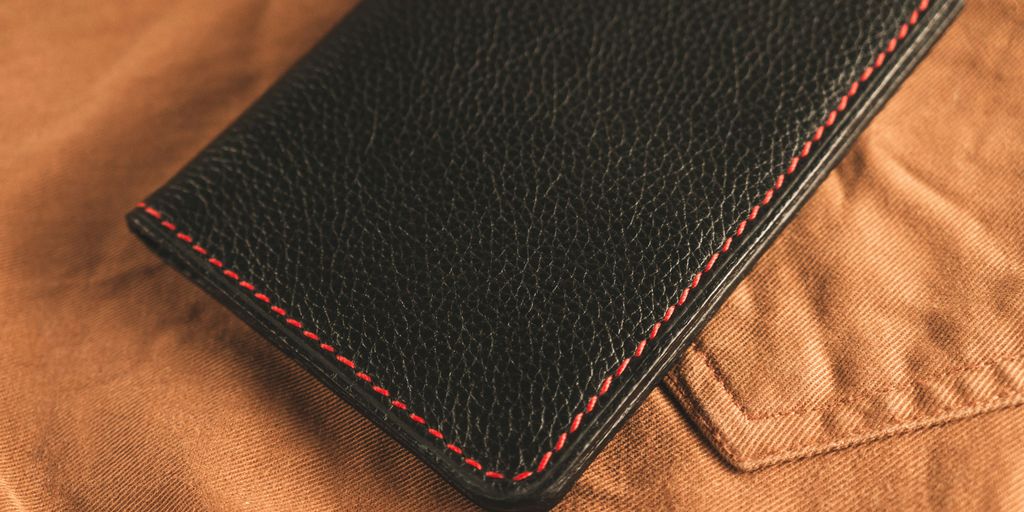 black leather bifold wallet on brown textile